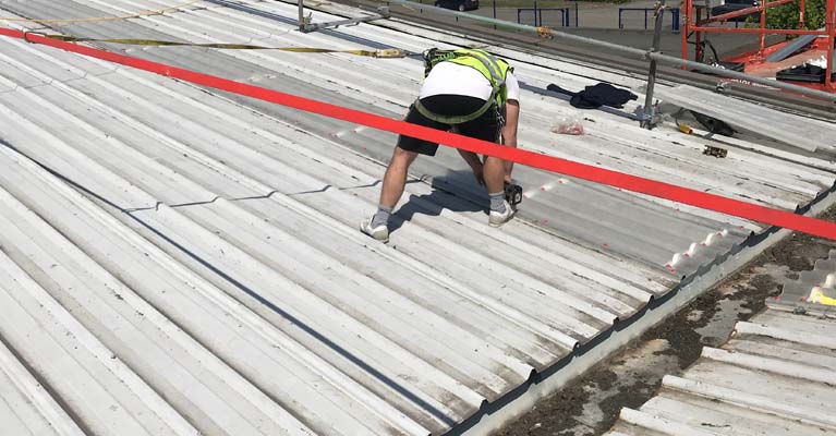 IRM roofer fixing down roof lights whilst harnessed and attached to a torque tensioned safety line.
