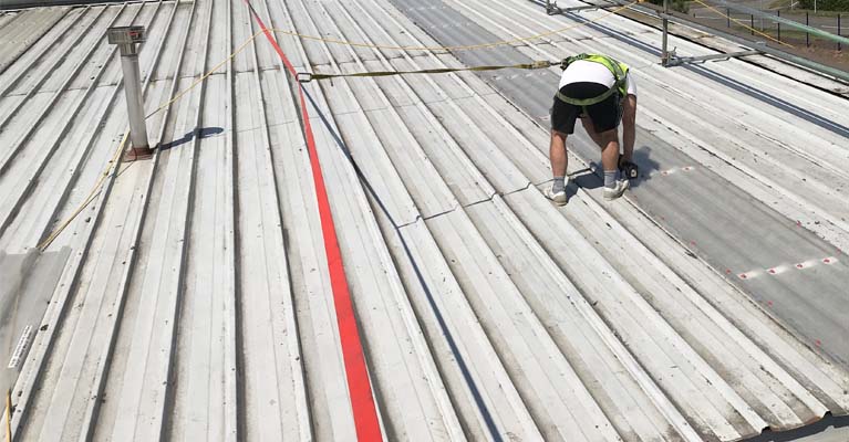 IRM Roofing installer attached to torque tensioned safety line.